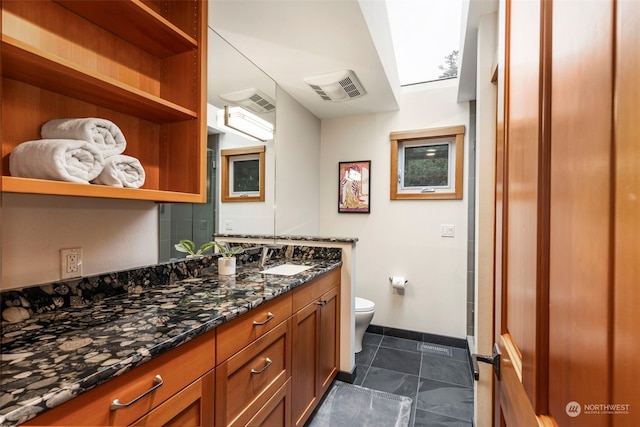 bathroom with vanity, toilet, and a skylight