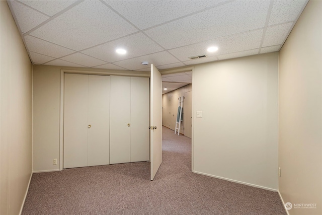 unfurnished bedroom featuring carpet, a paneled ceiling, and a closet