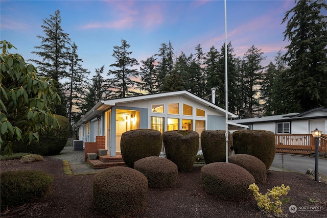 property exterior at dusk featuring central air condition unit and a wooden deck