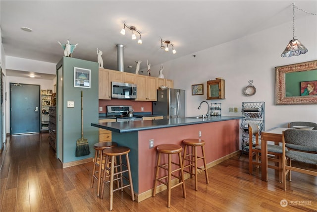 kitchen featuring light brown cabinetry, sink, appliances with stainless steel finishes, a kitchen breakfast bar, and hardwood / wood-style floors