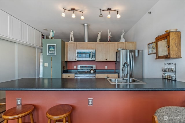 kitchen featuring a kitchen bar, sink, light brown cabinets, stainless steel appliances, and white cabinets