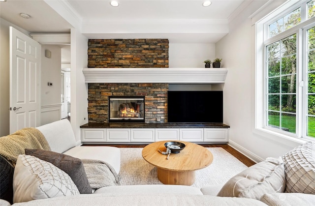 living room featuring crown molding, a fireplace, a healthy amount of sunlight, and hardwood / wood-style flooring