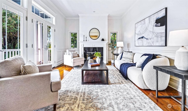 living room with a tile fireplace, crown molding, and wood-type flooring