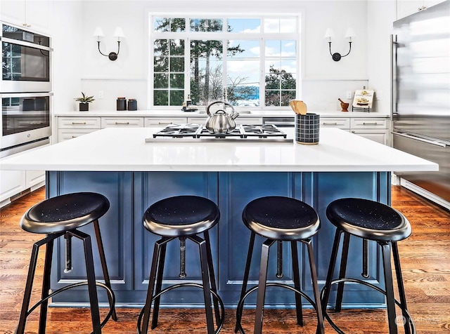 kitchen with a kitchen bar, appliances with stainless steel finishes, a center island, and white cabinets