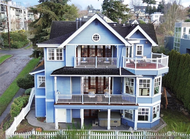 back of house featuring a hot tub and a balcony