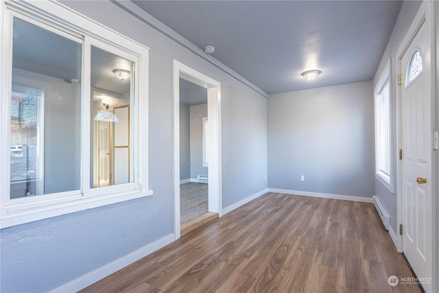 empty room with baseboard heating and dark hardwood / wood-style floors