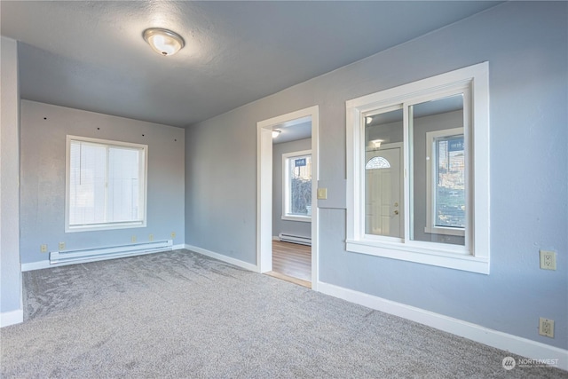 empty room featuring carpet flooring and a baseboard heating unit