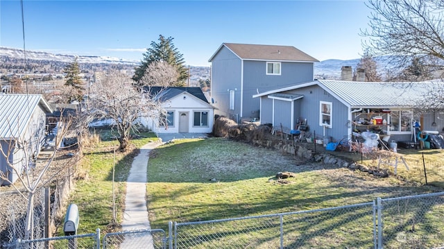 back of property with a mountain view and a yard