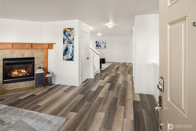 hall featuring dark wood-style flooring, baseboards, and stairs