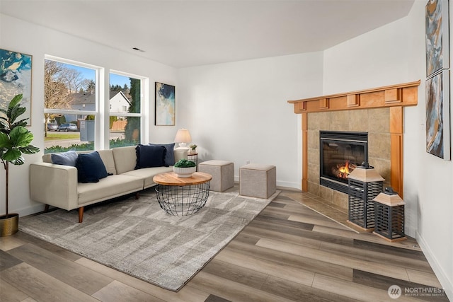 living room with visible vents, a fireplace, baseboards, and wood finished floors