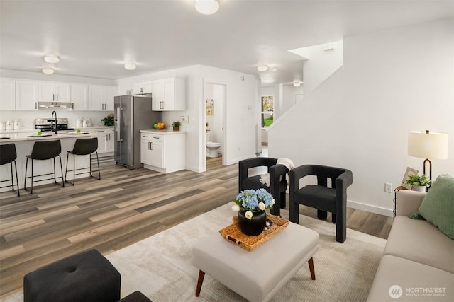 living room with light wood-style floors, baseboards, and stairs