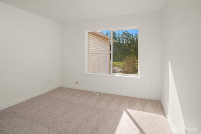 empty room with carpet, visible vents, and baseboards