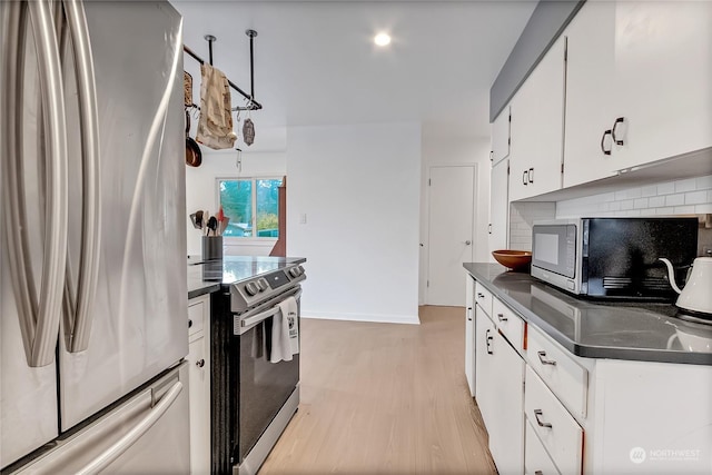 kitchen featuring light wood-type flooring, appliances with stainless steel finishes, backsplash, and white cabinetry