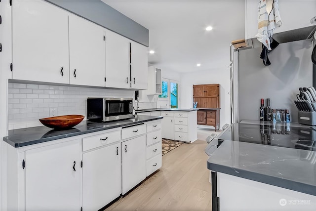 kitchen with tasteful backsplash, white cabinets, and light hardwood / wood-style floors