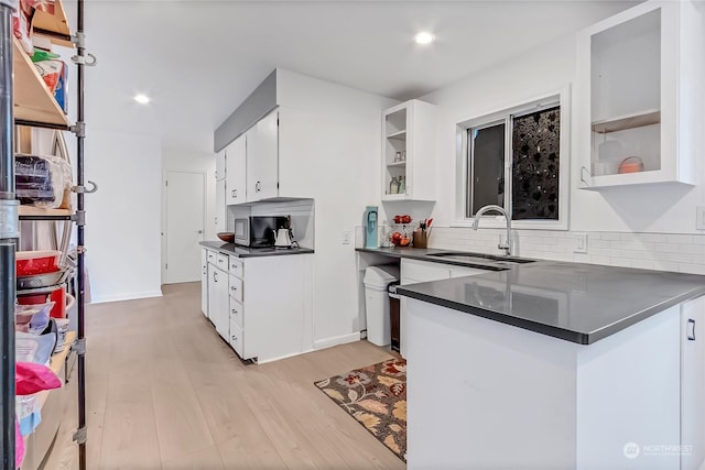 kitchen featuring backsplash, sink, white cabinets, and light hardwood / wood-style floors