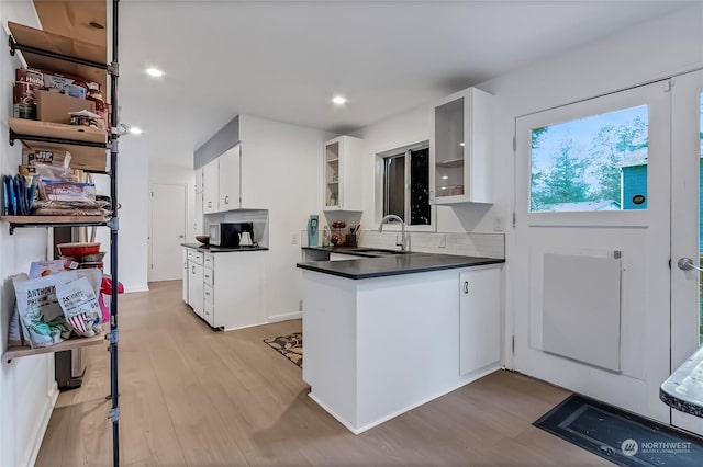 kitchen featuring white cabinets, decorative backsplash, light wood-type flooring, and sink