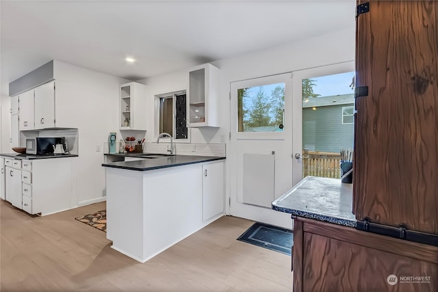 kitchen featuring kitchen peninsula, light hardwood / wood-style floors, white cabinetry, and sink