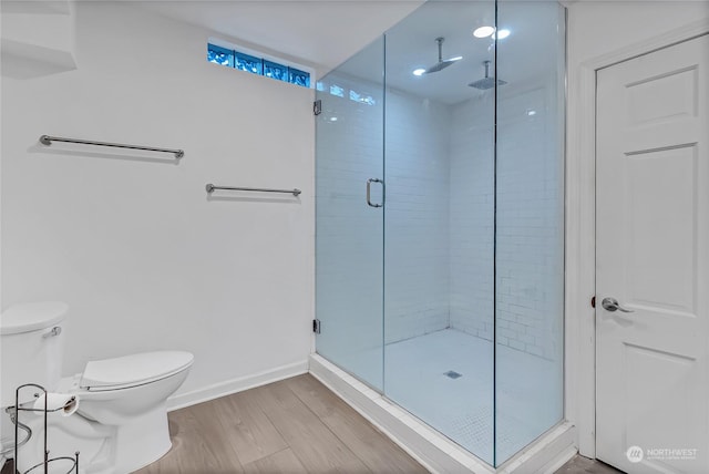 bathroom with toilet, a shower with shower door, and hardwood / wood-style flooring