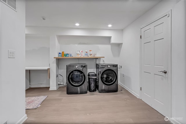 laundry room with light hardwood / wood-style floors and washing machine and clothes dryer