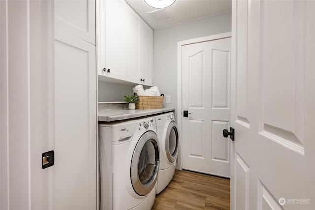 laundry area with cabinet space, washing machine and dryer, and light wood-style flooring