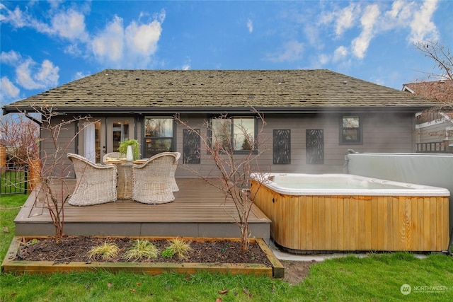 back of property with a shingled roof, a wooden deck, and a hot tub