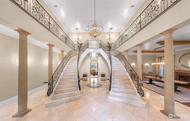 staircase with a high ceiling, ornamental molding, a chandelier, and ornate columns