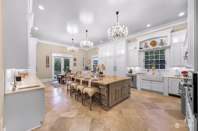 kitchen featuring white cabinets, dishwasher, hanging light fixtures, a kitchen island, and a breakfast bar