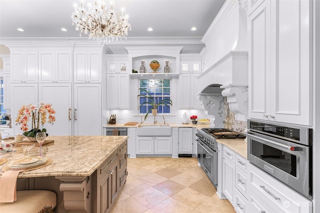 kitchen with appliances with stainless steel finishes, light stone countertops, sink, white cabinetry, and backsplash