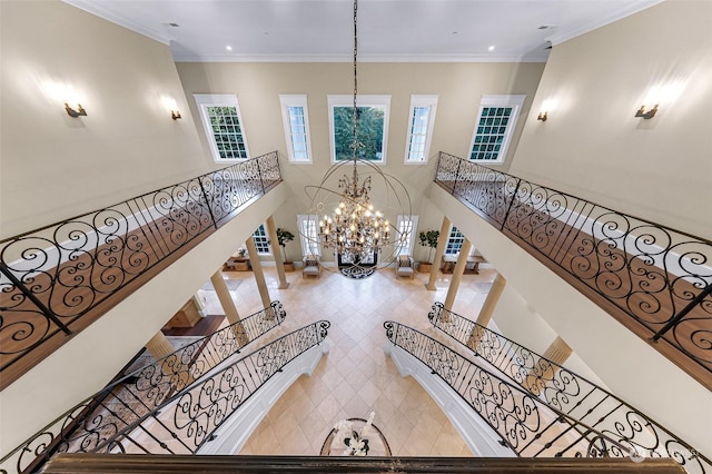 interior space with a towering ceiling, crown molding, and a chandelier