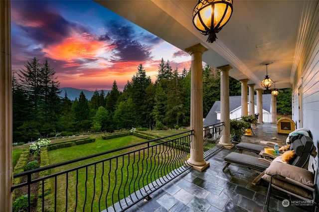 balcony at dusk featuring a porch