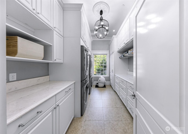 kitchen with white cabinets, hanging light fixtures, an inviting chandelier, and light stone counters