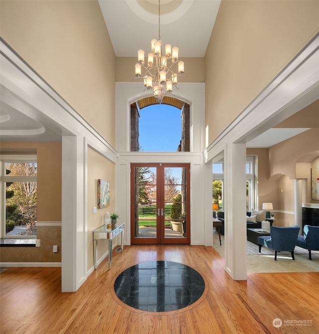 entryway featuring a high ceiling, an inviting chandelier, french doors, and plenty of natural light