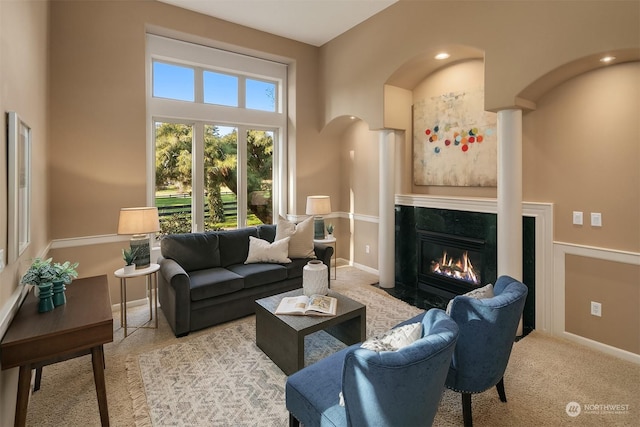 living room with light carpet, a towering ceiling, and a fireplace