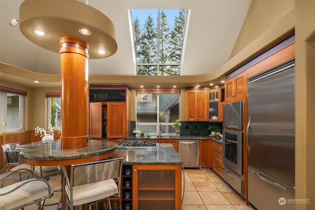 kitchen featuring sink, a center island, ornate columns, decorative backsplash, and appliances with stainless steel finishes