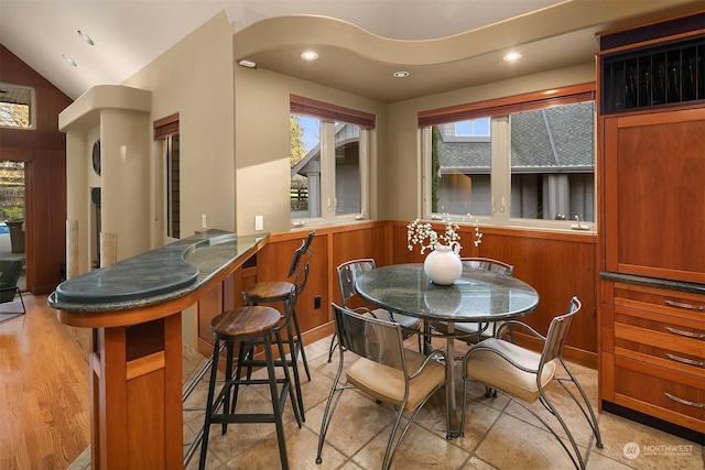 dining area with wood walls and lofted ceiling