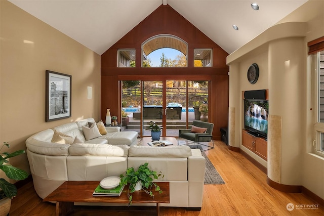 living room with light hardwood / wood-style flooring and high vaulted ceiling