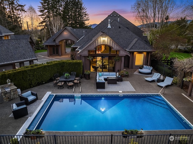 back house at dusk featuring an outdoor kitchen, a fenced in pool, an outdoor living space, and a patio