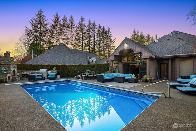 pool at dusk featuring a patio and an outdoor living space with a fireplace