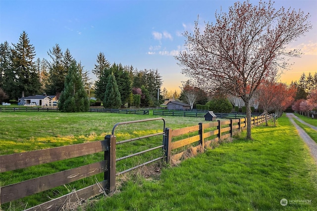 yard at dusk featuring a rural view