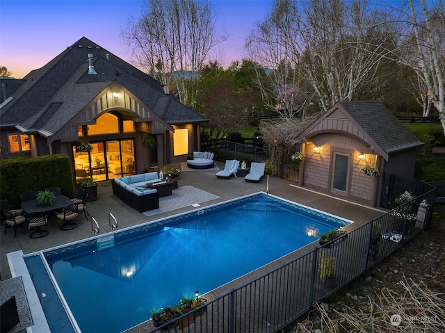 pool at dusk with a patio area, an outbuilding, and outdoor lounge area