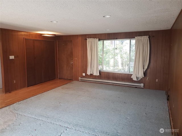 unfurnished room featuring a textured ceiling and a baseboard heating unit