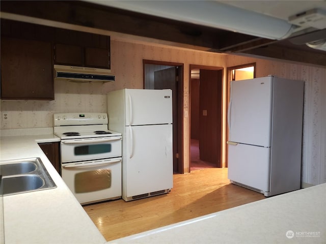 kitchen featuring sink, white appliances, light hardwood / wood-style flooring, and dark brown cabinets