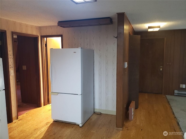 kitchen featuring a baseboard radiator, light wood-type flooring, a textured ceiling, and white fridge