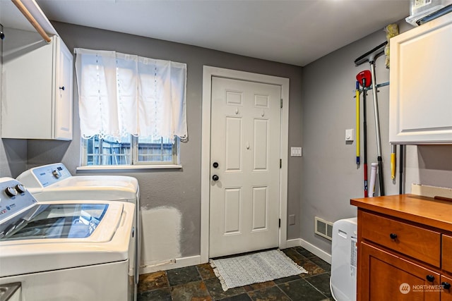 clothes washing area featuring cabinets and washer and clothes dryer