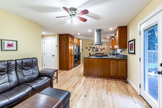 kitchen with kitchen peninsula, light hardwood / wood-style flooring, island range hood, stainless steel appliances, and ceiling fan