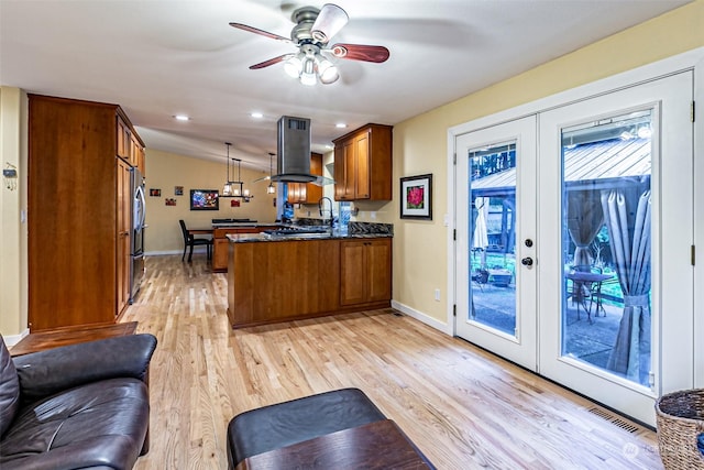 kitchen featuring decorative light fixtures, kitchen peninsula, french doors, and island exhaust hood