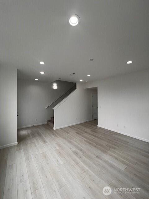 unfurnished living room featuring stairway, light wood finished floors, baseboards, and recessed lighting