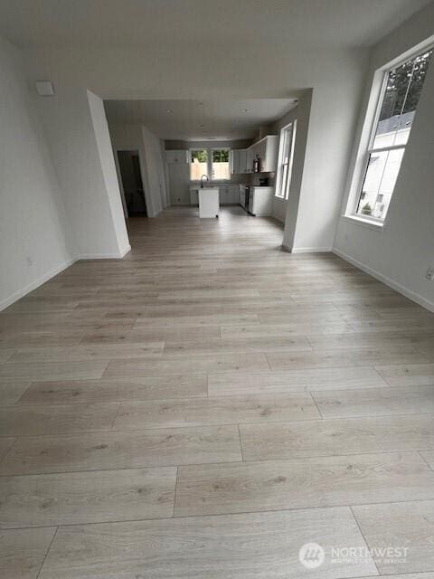 unfurnished living room with light wood-style flooring and baseboards