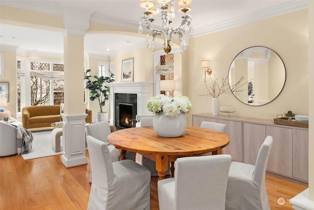 dining area with light wood-type flooring, ornamental molding, and decorative columns