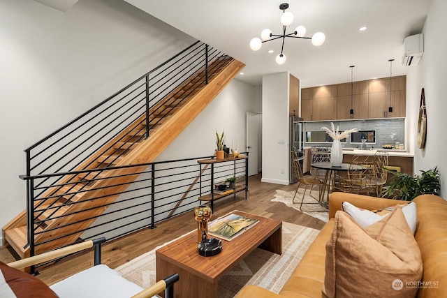 living room with a wall mounted air conditioner, light wood-type flooring, and an inviting chandelier